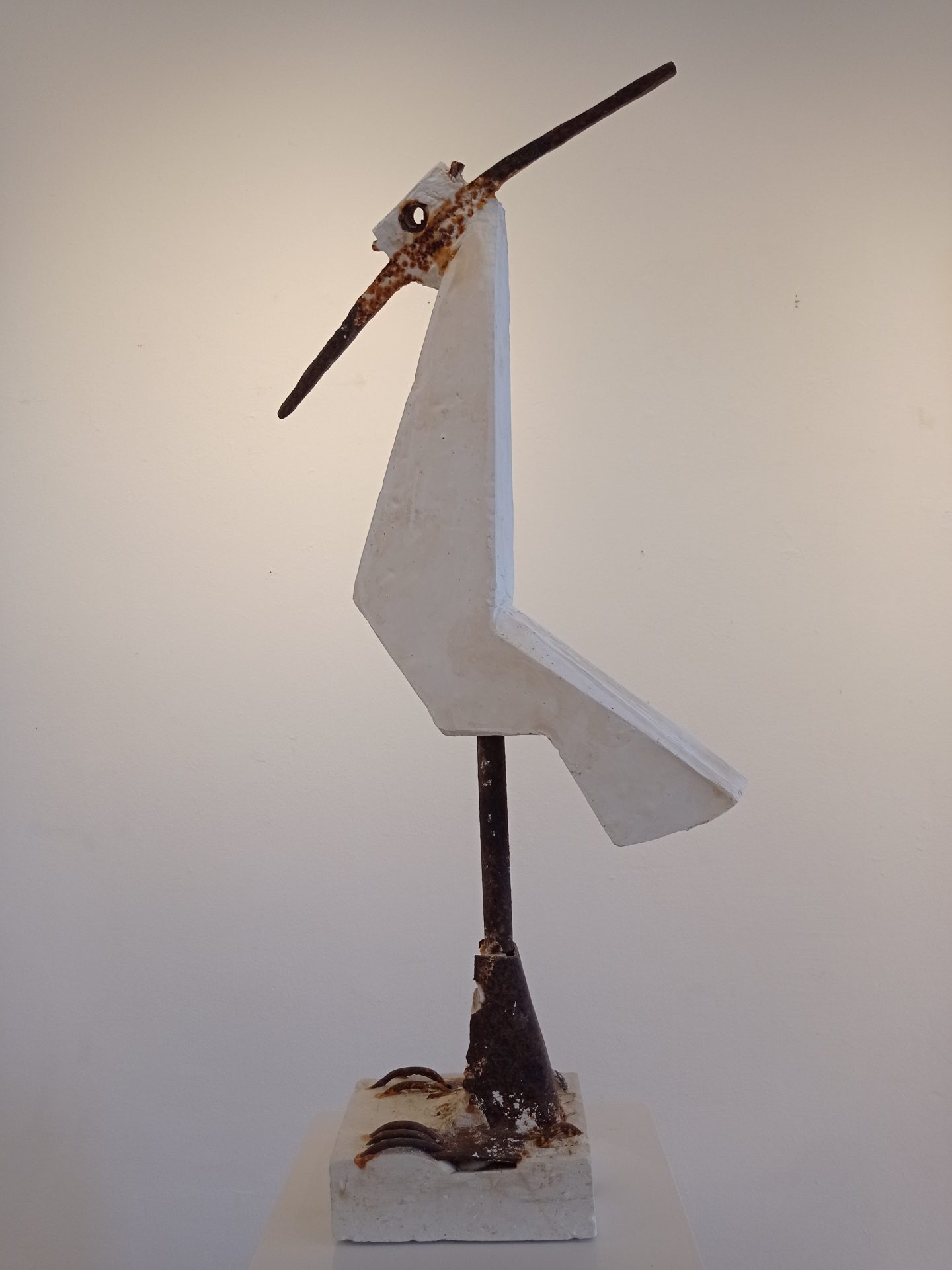 Objekt, das an einen Vogel erinnert. Im Original ist die Figur etwa ein Meter groß. Der Vogelkörper ist aus Gips geformt, die Beine sind ein Eisenrohr, die Füße sind Eisenteile, die an Krallen erinnern. Der Schnabel und der Federschopf am Hinterkopf werden durch eine verrostete Spitzhacke gebildet. Die Augen des Vogels sind ein Stück Eisenrohr, durch dass hindurchgeschaut werden kann. Objekt, das an einen Vogel erinnert.
Im Original ist die Figur etwa ein Meter groß. Der Vogelkörper ist aus Gips geformt, die Beine sind ein Eisenrohr, die Füße sind Eisenteile, die an Krallen erinnern.
Der Schnabel und der Federschopf am Hinterkopf werden durch eine verrostete Spitzhacke gebildet.
Die Augen des Vogels sind ein Stück Eisenrohr, durch dass hindurchgeschaut werden kann.